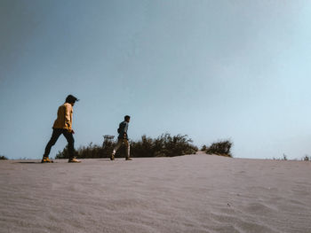 Low angle view of men standing on land against sky