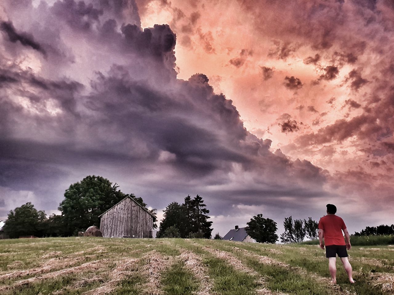 REAR VIEW OF MAN ON FIELD AGAINST SKY AT SUNSET