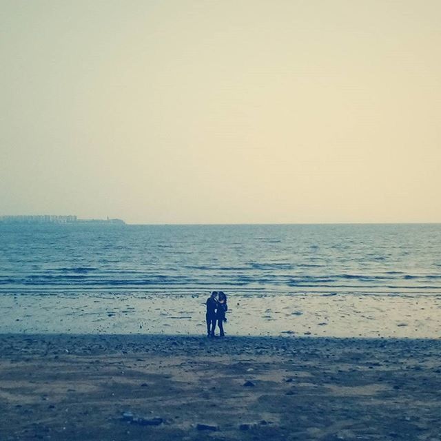 sea, water, horizon over water, beach, copy space, clear sky, shore, lifestyles, leisure activity, tranquil scene, full length, tranquility, scenics, men, standing, rear view, beauty in nature, nature