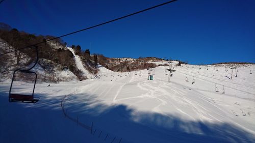 Overhead cable car on snowcapped mountains against clear blue sky