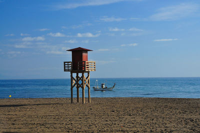Lifeguard hut at beach against blue sky on sunny day