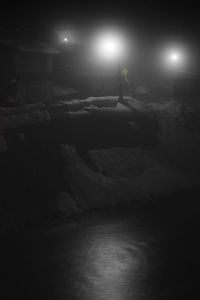 Side view of man standing on illuminated street lights at night