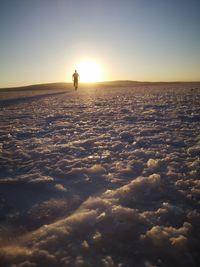 Silhouette person on land against sky during sunset