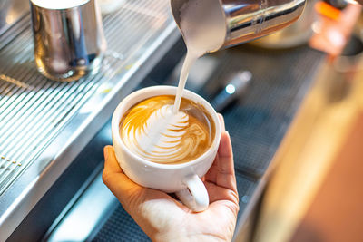 Midsection of person pouring coffee in cup