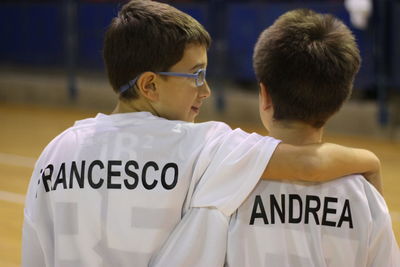 Rear view of siblings with arm around wearing t-shirt with text