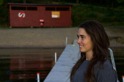 Beautiful woman standing on jetty against beach