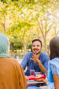 Portrait of smiling friends sitting in park