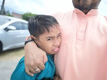 Portrait of cute boy standing with father on road 