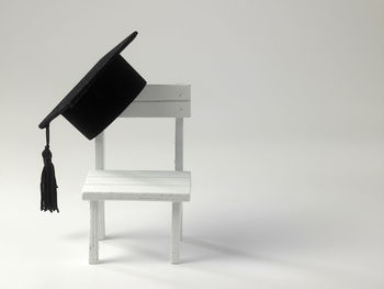 Figurine chair with mortarboard against white background