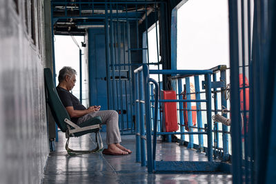 Man sitting in boat on sea against sky