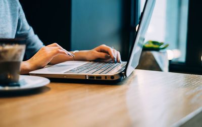 Close-up of man using laptop on table