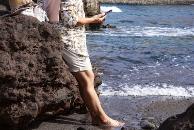 Low section senior woman standing at beach