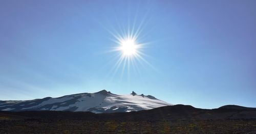 Scenic view of snowcapped mountains against blue sky