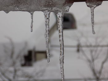 Close-up of icicles hanging against sky during winter