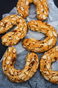 Crescent shaped baked almond cookies textured with sliced almonds arranged on waxed paper 