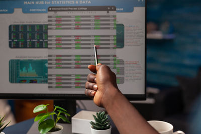 Cropped hand of man pointing on computer monitor