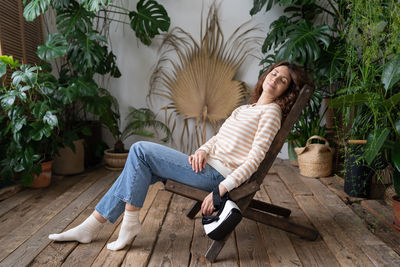 Tired young woman with vr glasses in arm take nap daydreaming in living room with tropical plants.