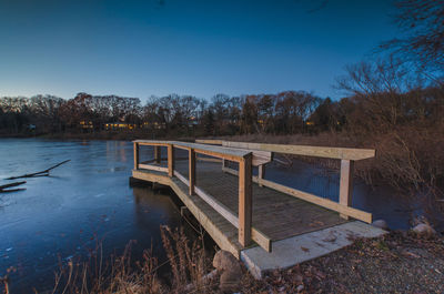 Built structure by calm lake against blue sky