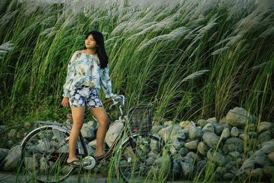 Teenage girl with bicycle by plants