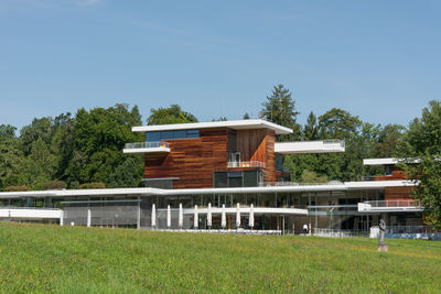 Houses on field by building against sky