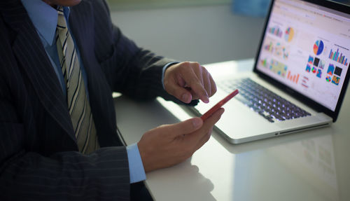 Midsection of businessman using technologies at desk in office