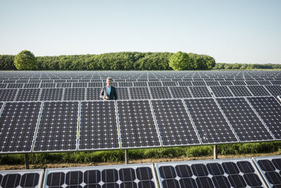 Mature man standing on panel in solar plant