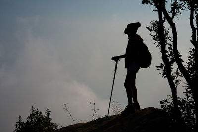 Low angle view of silhouette woman hiking on mountain against sky