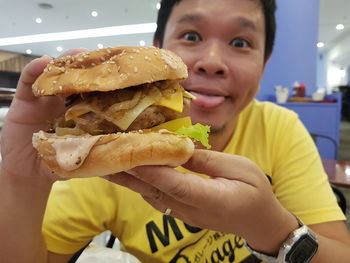 Portrait of man having burger at restaurant