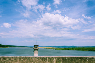 Lighthouse by sea against sky