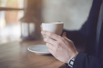 Cropped image of businessman having coffee while sitting at table