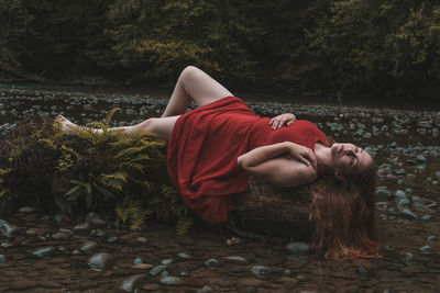 Woman lying on log amidst log in forest