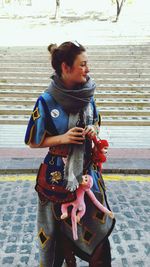 Young woman holding camera while standing outdoors