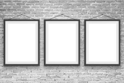 Close-up of blank picture frames hanging on brick wall