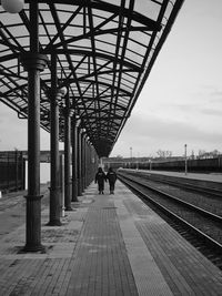 People walking on railroad track against sky