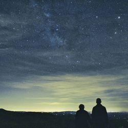 Person standing on landscape against sky at night