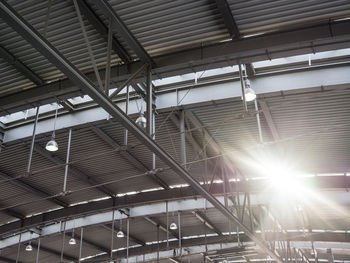 Low angle view of sun shining through roof of train station