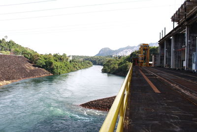 Railroad track by river against sky