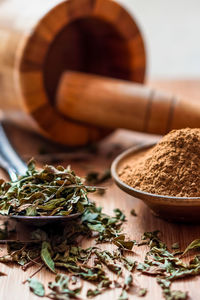 Close-up of leaves and powder in container by mortar and pestle