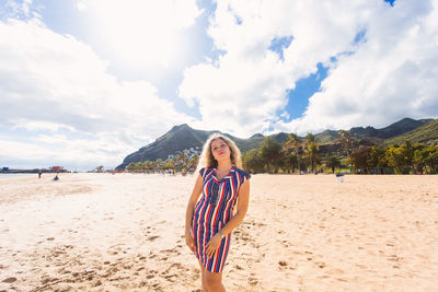 Portrait of woman standing on beach against sky