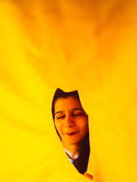 Portrait of young man standing against orange yellow background