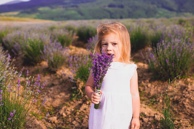 Woman standing by purple flower on field