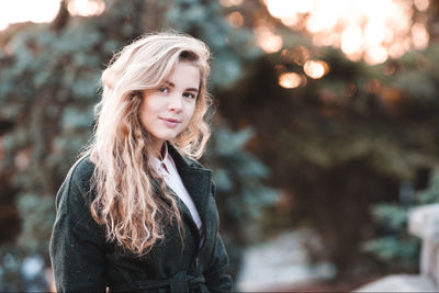 Portrait of beautiful woman standing in front of trees