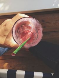 Close-up of hand holding drink on table