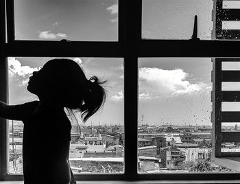 Side view of silhouette woman looking through window