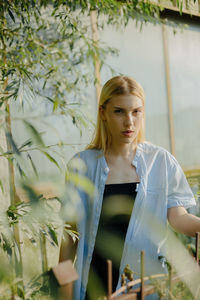 Young woman looking away while standing against plants