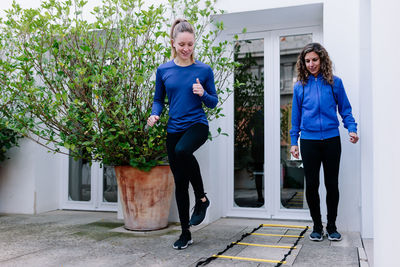 Full length of woman smiling while standing against plants