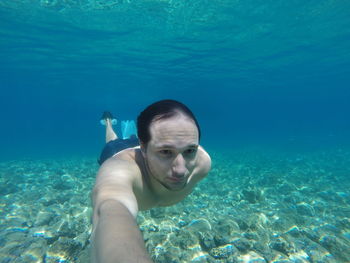 Shirtless man swimming in sea