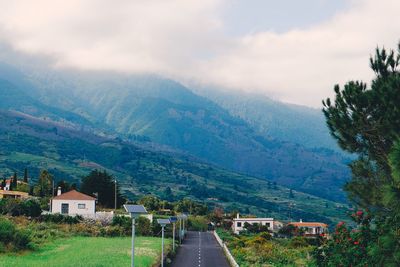 Road by mountains against sky