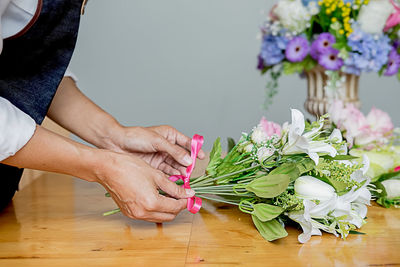 Close-up of hand holding bouquet of flowers on table