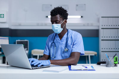 Male nurse working on laptop in office